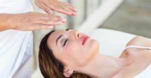 Reiki practitioner holding hands near a client's head during a healing session